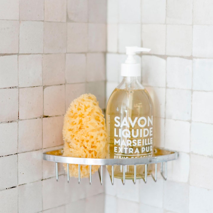 Compagnie de Provence Cotton Flower 495 ml mild håndsåpe i klar flaske med hvit pumpe på baderomshylle med natursvamp.