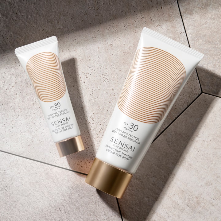 Sensai Silky Bronze Protective Cream Face 50 ml SPF 30 solkrem i hvit tube med gullmønster på grå steinfliser.