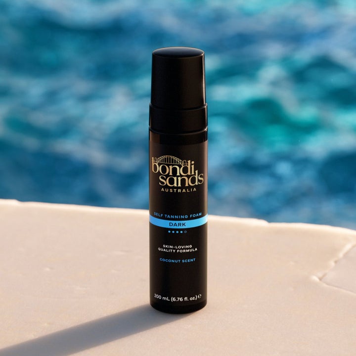 Bondi Sands Self Tanning Foam Dark 200 ml for dyp glød i svart pumpeflaske foran et blått basseng
