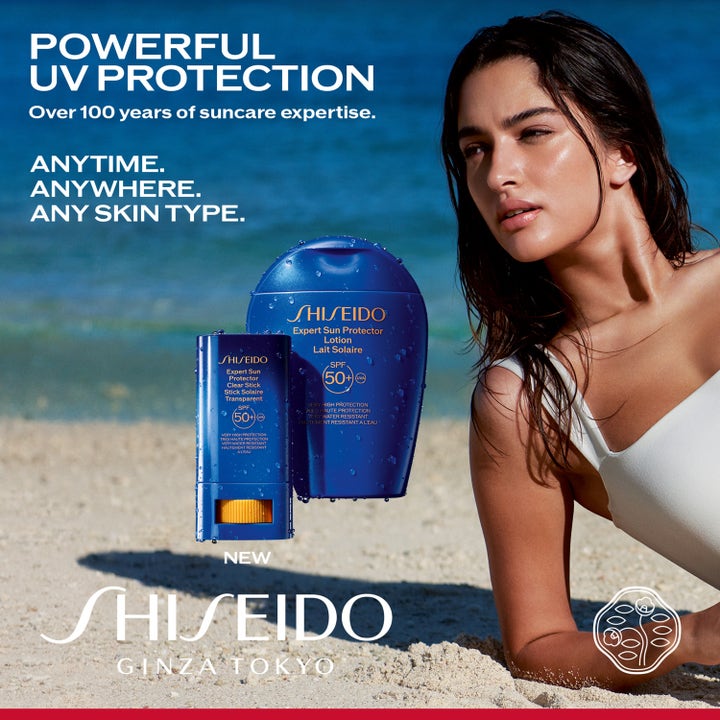 Shiseido Global Sun Care Clear Stick 20 g solstift med SPF 50+ i blå beholder på en strand med en kvinne