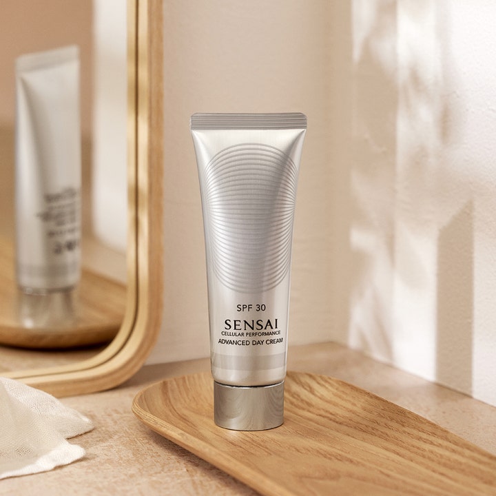 Sensai Cellular Performance Advanced Day Cream SPF30 50 ml i sølvfarget tube på et trefat foran et speil
