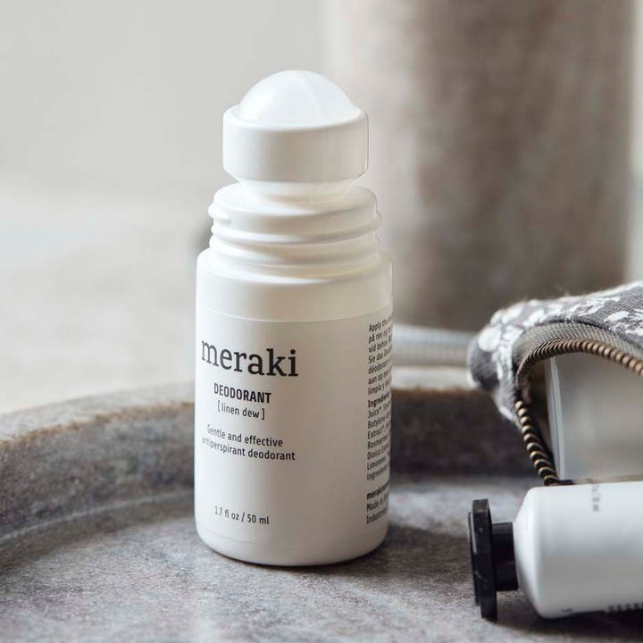 Meraki Deodorant Linen Dew 50 ml mild antiperspirant i hvit roll-on-flaske uten kork plassert på et steinfat.