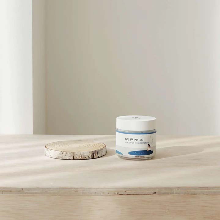 Round Lab Birch Juice Moisturizing Cream 80 ml fuktighetskrem i krukke ved siden av en dekorativ bjørkeskive.