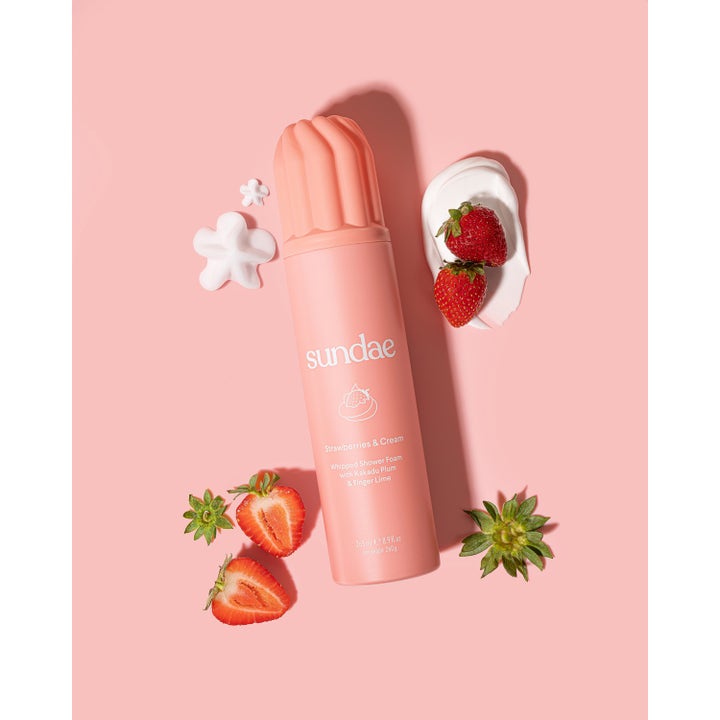 Sundae Whipped Shower Foam Strawberries & Cream 265 ml dusjsåpe i rosa flaske omgitt av ferske jordbær og skum