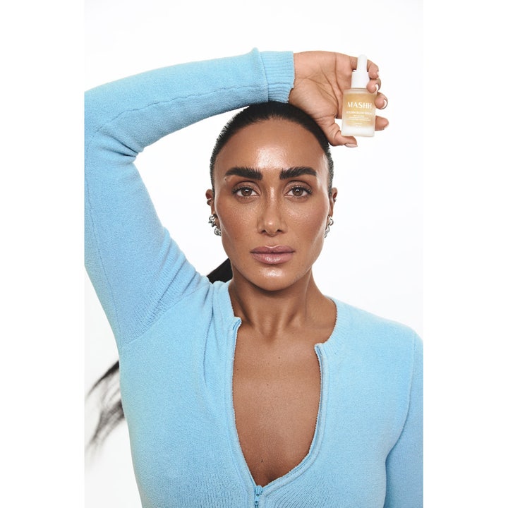 MASHH Golden Glow Serum 30 ml glødgivende ansiktsserum i frostet glassflaske holdt av kvinne med sunn glød.