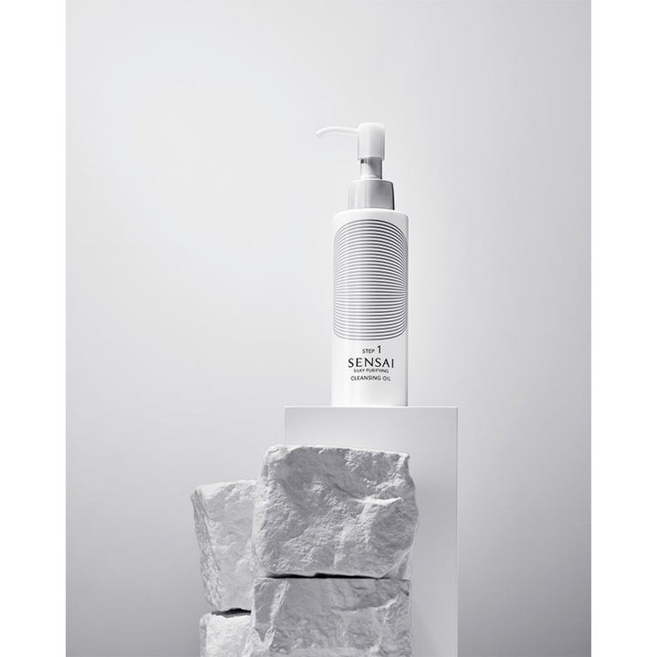 Sensai Silky Purifying Cleansing Oil Step 1 renseolje i hvit pumpeflaske med grafisk mønster ved hvite steiner
