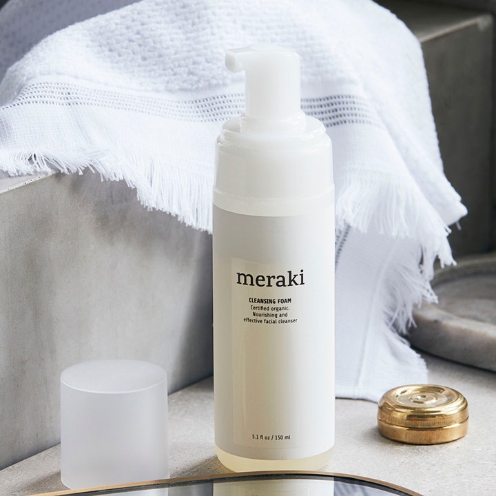 Meraki Cleansing Foam 150 ml pleiende ansiktsrens i hvit flaske med pumpe plassert ved et mykt hvitt håndkle