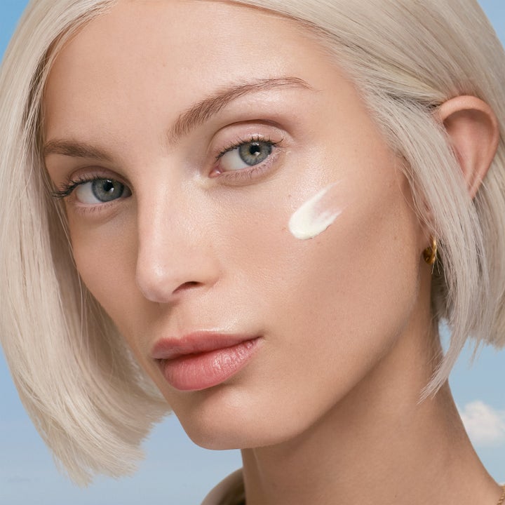 Lancaster Sun Perfect AIR Invisible Fluid 40 ml solkrem med hvit tekstur på en kvinnes kinn
