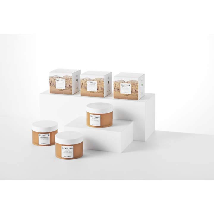 SKIN1004 Madagascar Centella Quick Calming Pad 130 ml beroligende pads i ravfargede krukker og esker på hvite podier