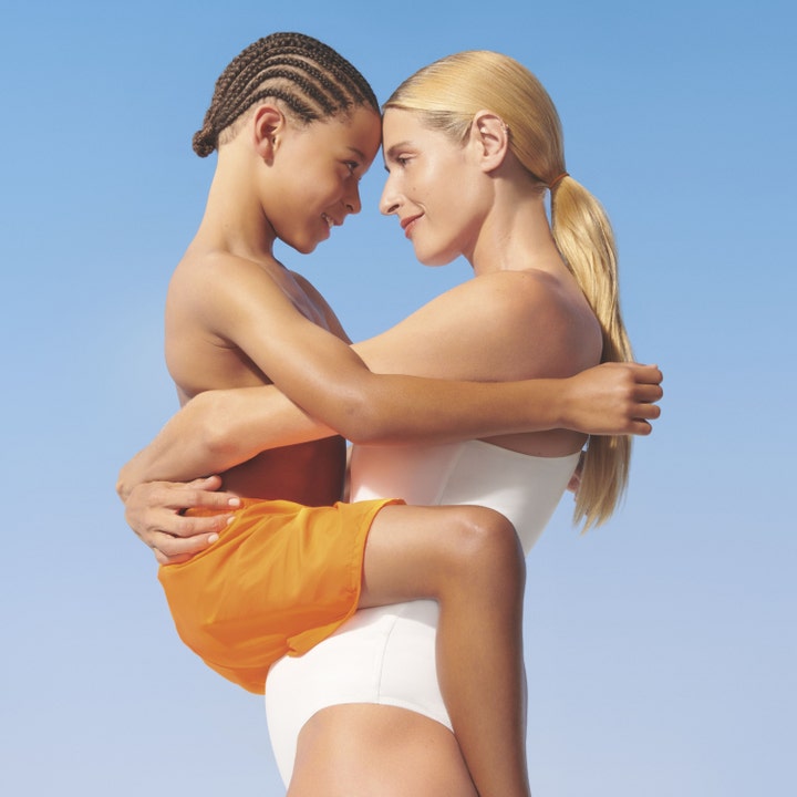 Garnier Ambre Solaire Kids Lotion SPF50+ 175 ml solkrem til barn vist ved en mor som holder barnet sitt mot en blå himmel