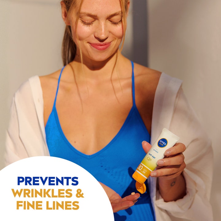 NIVEA Sun UV Face Anti Age Q10 Cream 50 ml solkrem ansikt som forebygger rynker vist mens kvinne påfører krem fra tube.
