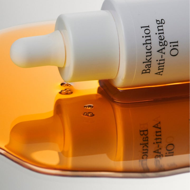 Jorgobé Bakuchiol Anti-Ageing Oil 30 ml ansiktsolje i hvit pipetteflaske over en gyllen og flytende oljetekstur.