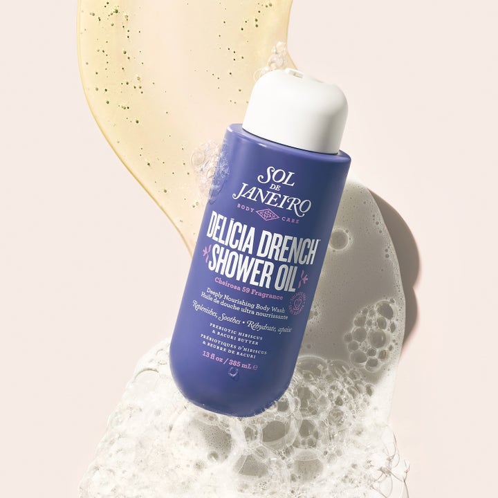 Sol de Janeiro Delicia Drench Shower Oil 385 ml lilla flaske med hvit kork og gyllen oljetekstur med skum
