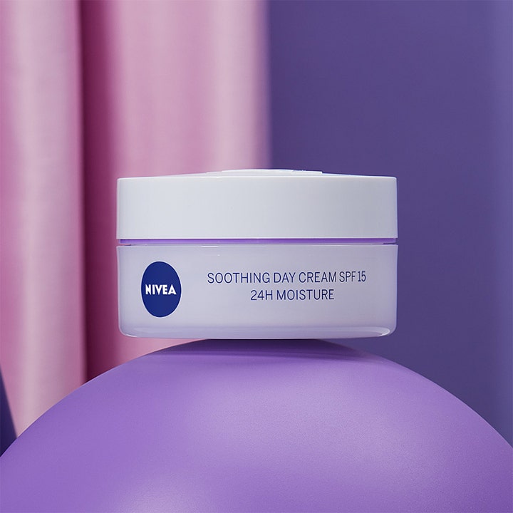NIVEA Soothing Day Cream SPF15 50 ml beroligende dagkrem i lilla krukke plassert på en lilla kule med rosa bakgrunn