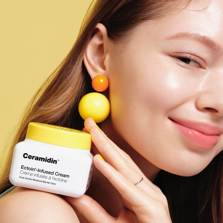 Dr.Jart+ Ceramidin Ectoin-Infused Cream 50 ml styrkende ansiktskrem vist av kvinne med sunn glød og gule øredobber.