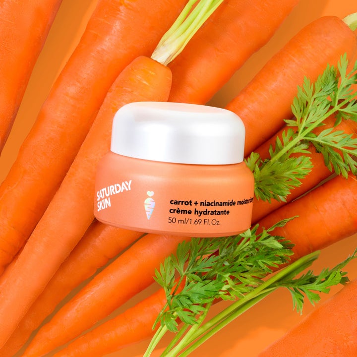 Saturday Skin Carrot + Niacinamide Moisturizing Cream 50 ml fuktighetskrem i oransje krukke plassert på ferske gulrøtter