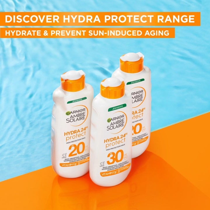 Garnier Ambre Solaire Hydra 24H Protect 175 ml fuktighetsgivende solkrem i hvite flasker ved et blått basseng