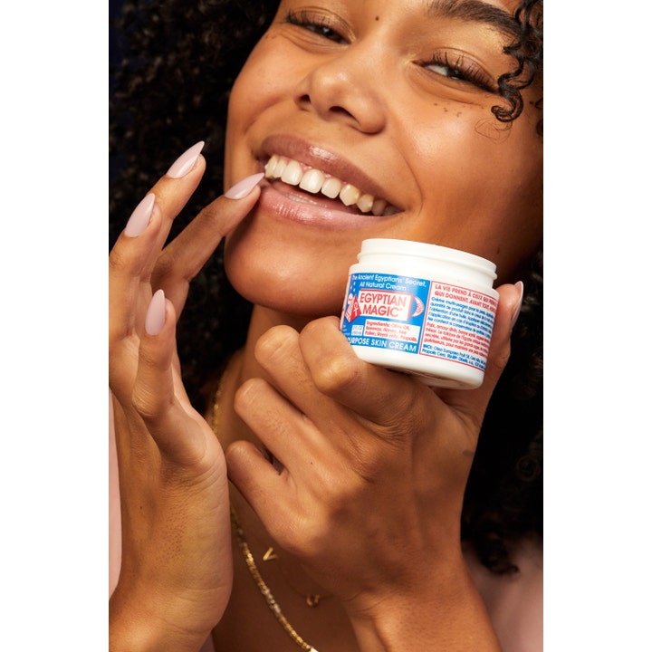 Egyptian Magic All Purpose Skin Cream 59 ml fuktighetsgivende multikrem i krukke holdt av en smilende kvinne