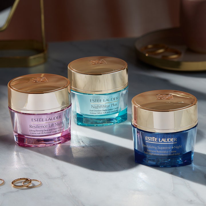 Estée Lauder NightWear Plus 50 ml nattkrem i turkis glasskrukke med gulllokk ved siden av andre ansiktskremer