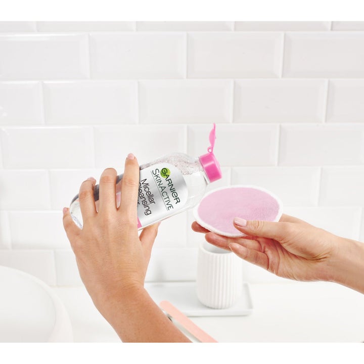 Garnier Micellar Water og Eco Pads ansiktsrens fjerner sminke idet væsken helles på en rosa gjenbrukbar Eco Pad.