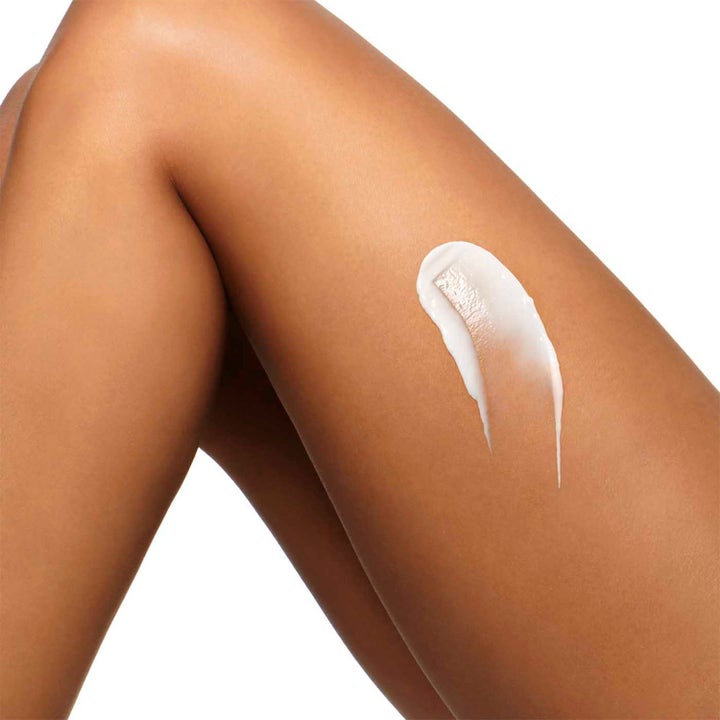 Clarins Hydrating Body-Smoothing Moisture Milk 400 ml fuktighetsgivende body lotion med hvit kremet tekstur på et ben
