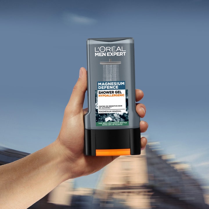 L'Oréal Paris Men Expert Magnesium Defence 300 ml dusjsåpe som beroliger sensitiv hud holdes i en hånd utendørs.