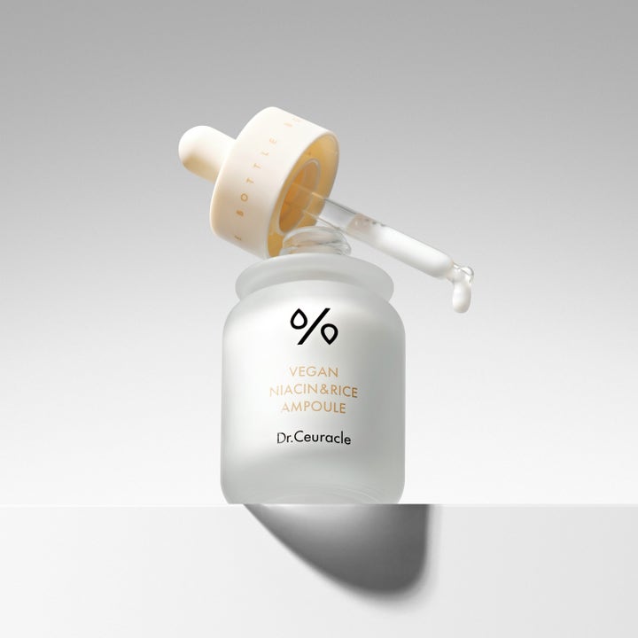 Dr. Ceuracle Vegan Niacin & Rice Ampoule 30 ml serum med melkehvit tekstur på en pipette over hvit frostet glassflaske