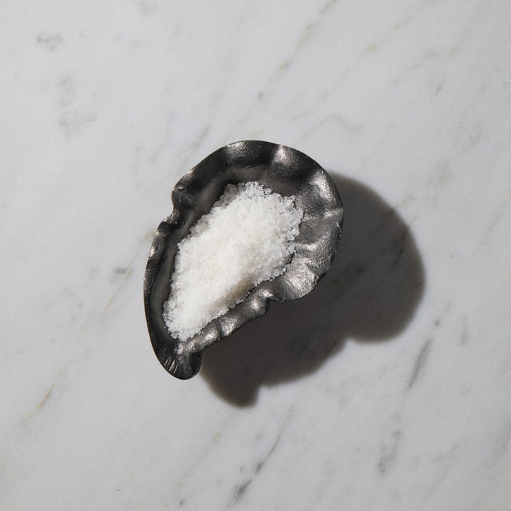Bodyologist Calming Crystals 250 g beroligende badesalt i mørk skål på marmorbakgrunn for et avslappende bad