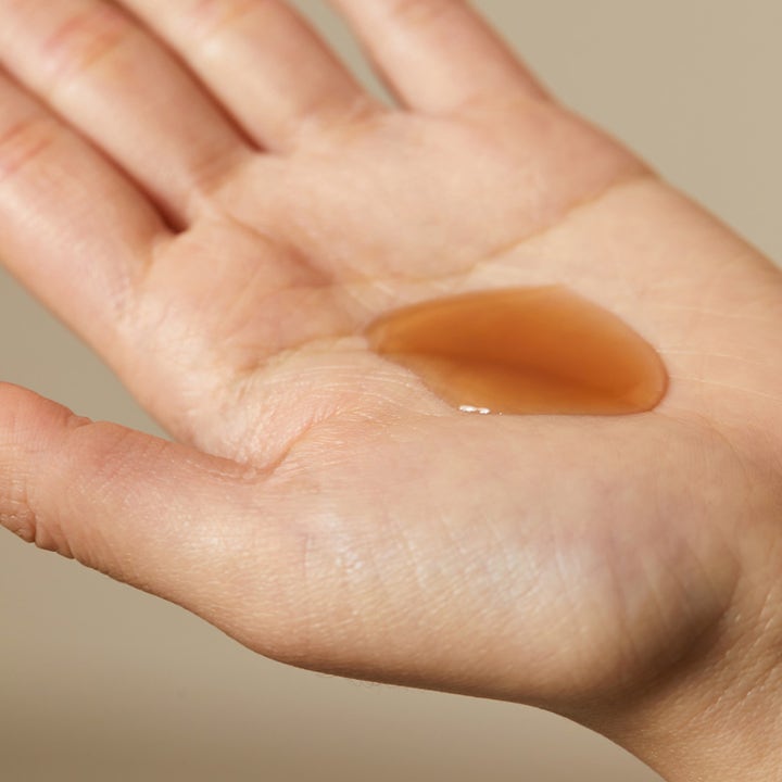 Hyggee Natural Repair Serum 120 ml reparerende ansiktsserum med en ravfarget flytende tekstur i en håndflate
