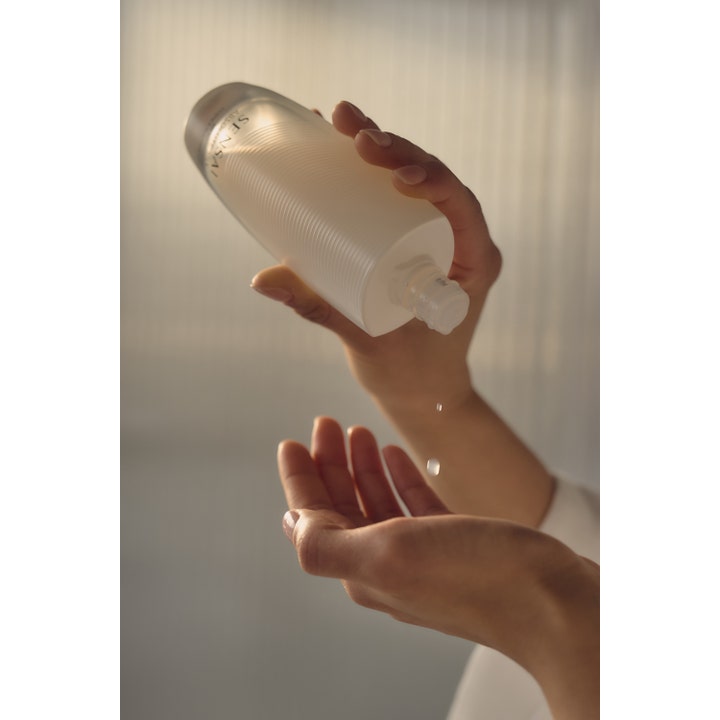 Sensai Absolute Silk Micro Essence-In-Lotion 125 ml serum som helles fra en riflet flaske ned i en hånd.