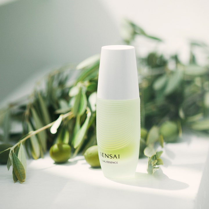 Sensai Dual Essence 30 ml to-faset ansiktsbehandling i hvit flaske plassert ved friske olivengrener