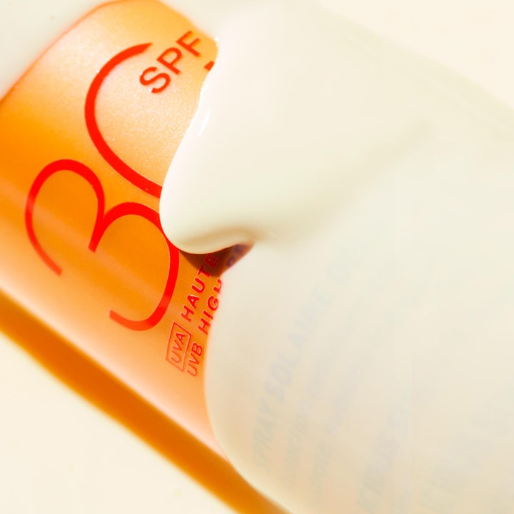Nuxe Sun Spray SPF30 184 g solkrem med hvit kremet tekstur som renner over den oransje flasken