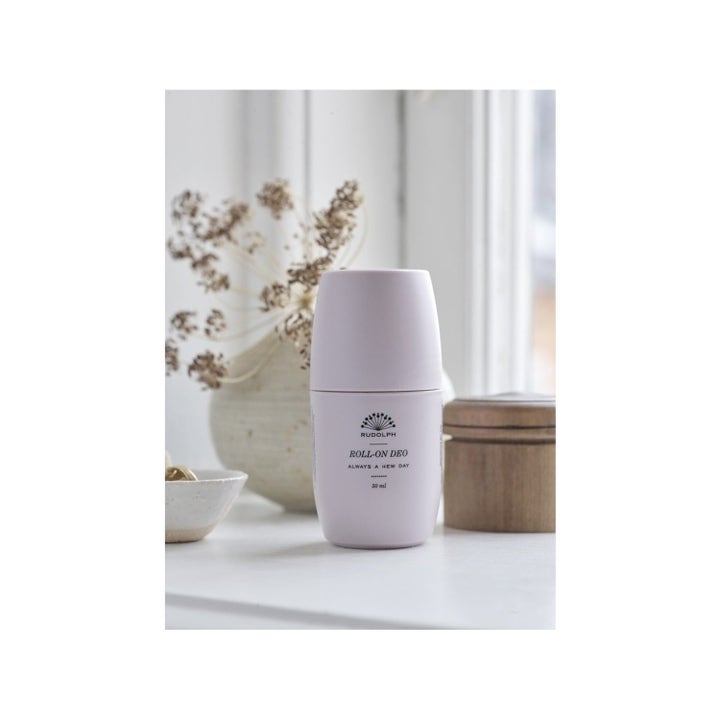 Rudolph Care Acai Keep On Rolling Duo 50 ml pleiende deodorant i lys rosa flaske plassert i et lyst miljø.