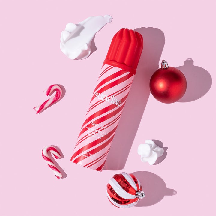 Sundae Candy Cane Whipped Shower Foam 265 ml pleiende dusjsåpe med polkastenger og julekuler på rosa flate.