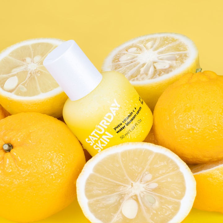 Saturday Skin Yuzu Vitamin C + Water Blossom Serum 50 ml ansiktsserum i gul flaske omgitt av friske yuzufrukter