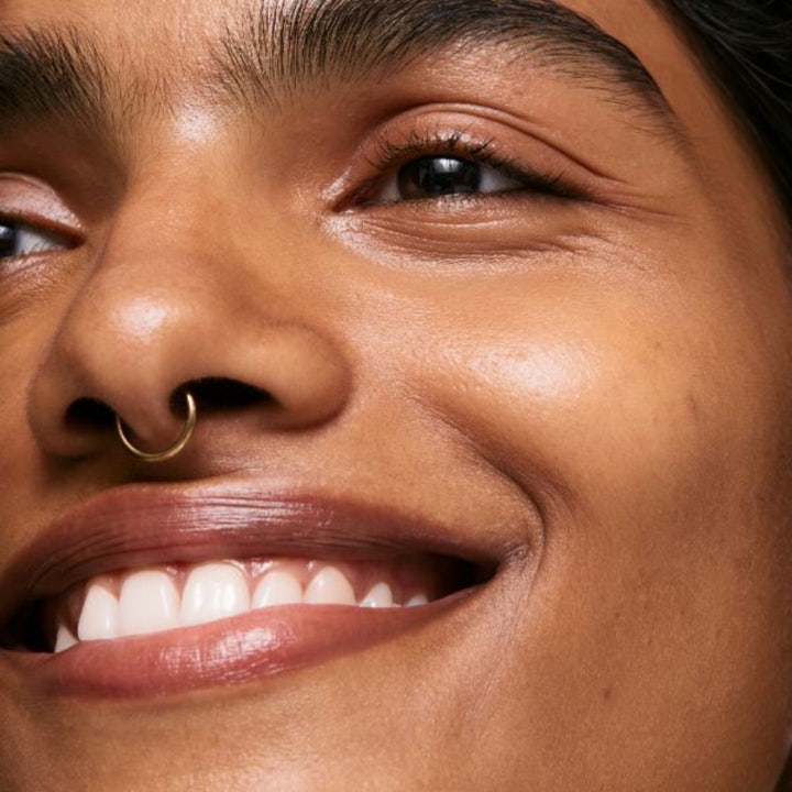 The INKEY List Brighten-i Eye Cream 15 ml øyekrem mot mørke ringer gir glød til huden vist på en smilende person.