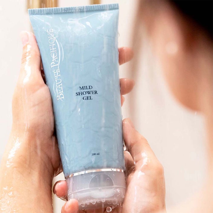 Beauté Pacifique Mild Shower Gel 200 ml rensende dusjsåpe i lyseblå tube dekket av vanndråper i våte hender