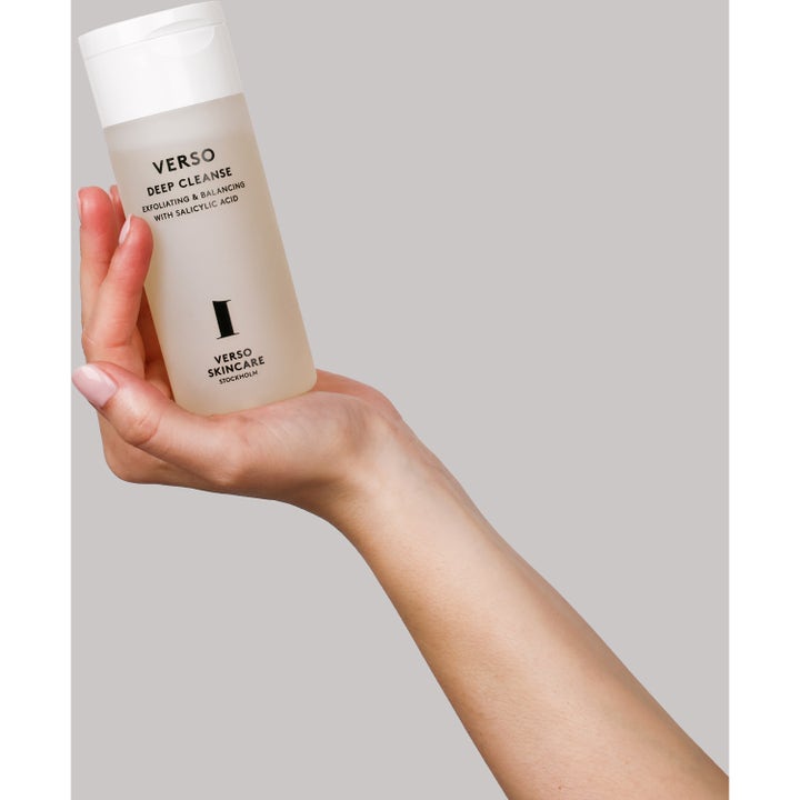 Verso N°1 Deep Cleanse 150 ml eksfolierende ansiktsrengjøring med salisylsyre i frostet flaske holdt av en hånd