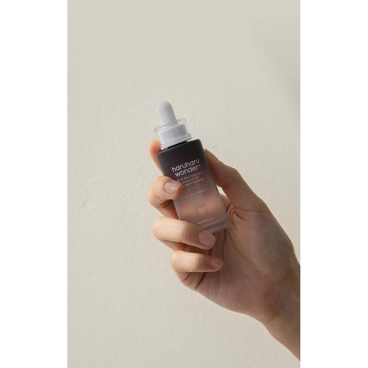 Haruharu Wonder Black Rice Hyaluronic Botanical 2GF Ampoule 30 ml fuktserum i mørk glassflaske holdt av en hånd