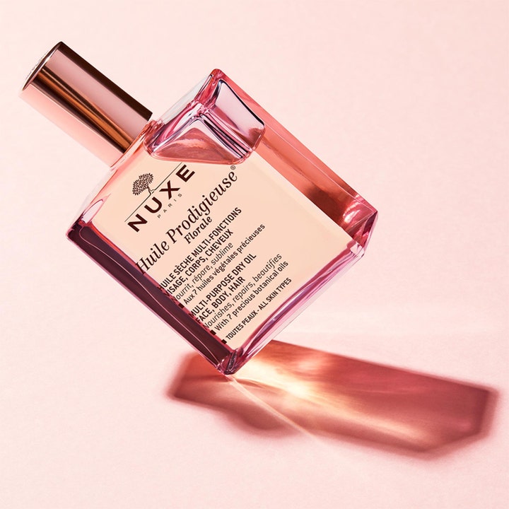Nuxe Huile Prodigieuse Florale 100 ml nærende tørrolje i en rosa glassflaske som står på skrå mot en rosa bakgrunn