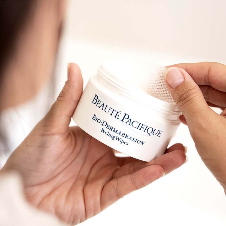 Beauté Pacifique Bio-Dermabrasion Peeling Wipes fornyende hudpleie i hvit krukke der en teksturert pad løftes ut.