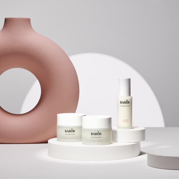 Babor Calming Serum 30 ml beroligende ansiktsserum i hvit glassflaske på hvite podier med en støvrosa vase.