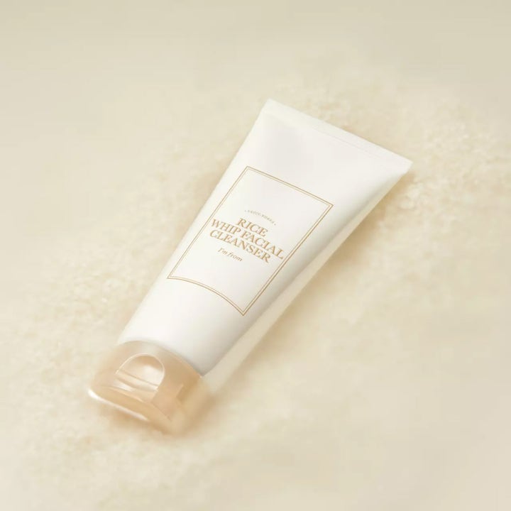 I'm from Rice Whip Facial Cleanser 150 ml ansiktsrengjøring i hvit tube liggende på en seng av glødgivende riskorn