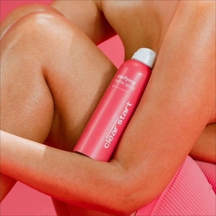 Dermalogica Clarifying Body Spray Duo med salisylsyre motvirker kviser i en rosa sprayflaske holdt mot bar hud