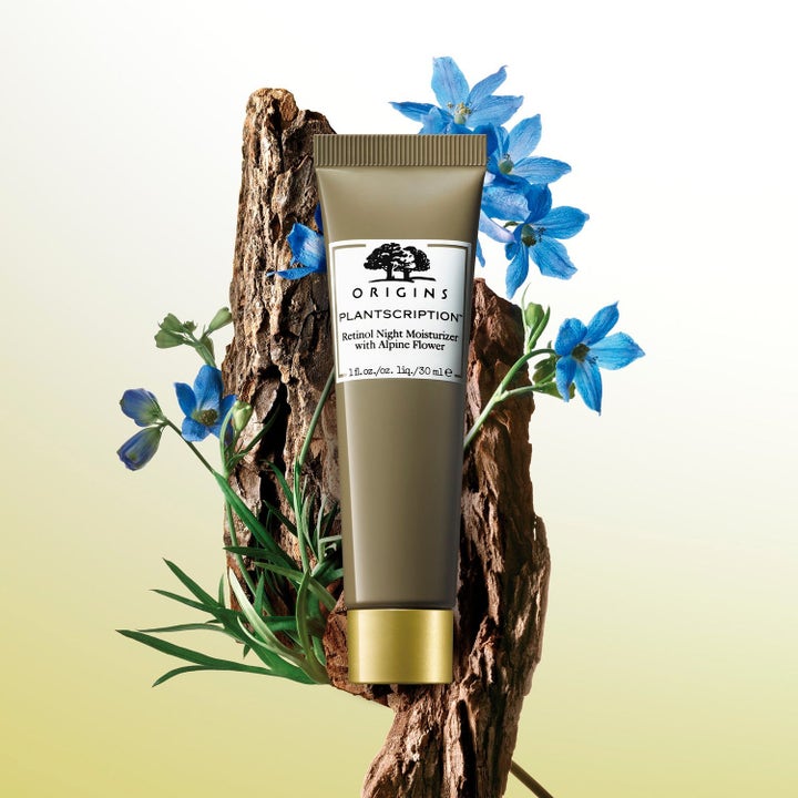 Origins Plantscription Retinol Night Moisturizer 30 ml nattkrem i olivegrønn tube med gullkork foran bark og blå blomster