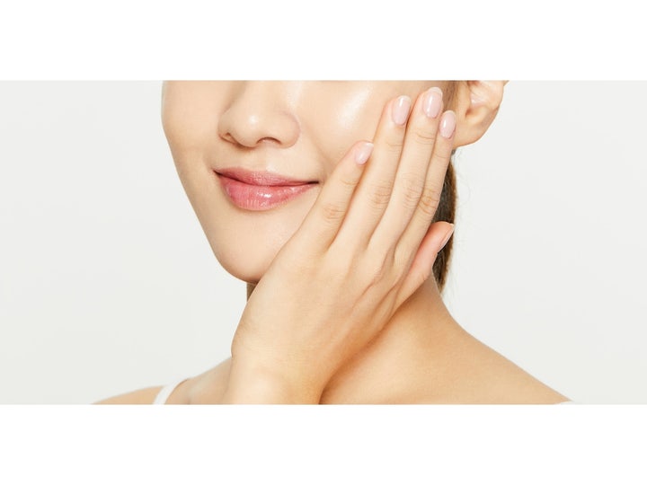 COSRX Oil Free Ultra Moisturizing Lotion 100 ml fuktighetskrem som gir sunn glød vist på en kvinne som berører kinnet.