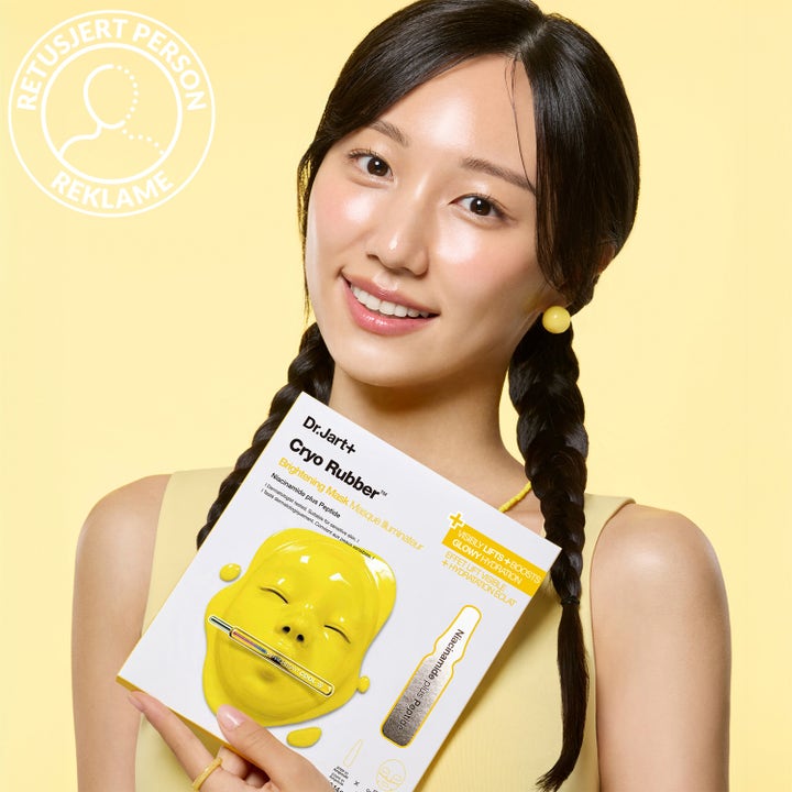 Dr.Jart+ Cryo Rubber Brightening Mask 36 g ansiktsmaske med niacinamide og peptide holdt av kvinne i gul setting.