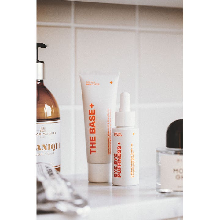 Swiss Clinic Bye Bye Puffiness+ 30 ml energigivende øyekrem mot hovne øyne i hvit flaske med pipette på et bad