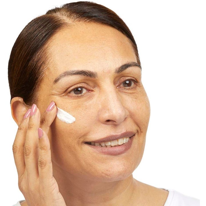 No7 Restore & Renew Skincare Essential Set 80 ml gir fastere hud kvinne påfører hvit ansiktskrem på kinnet