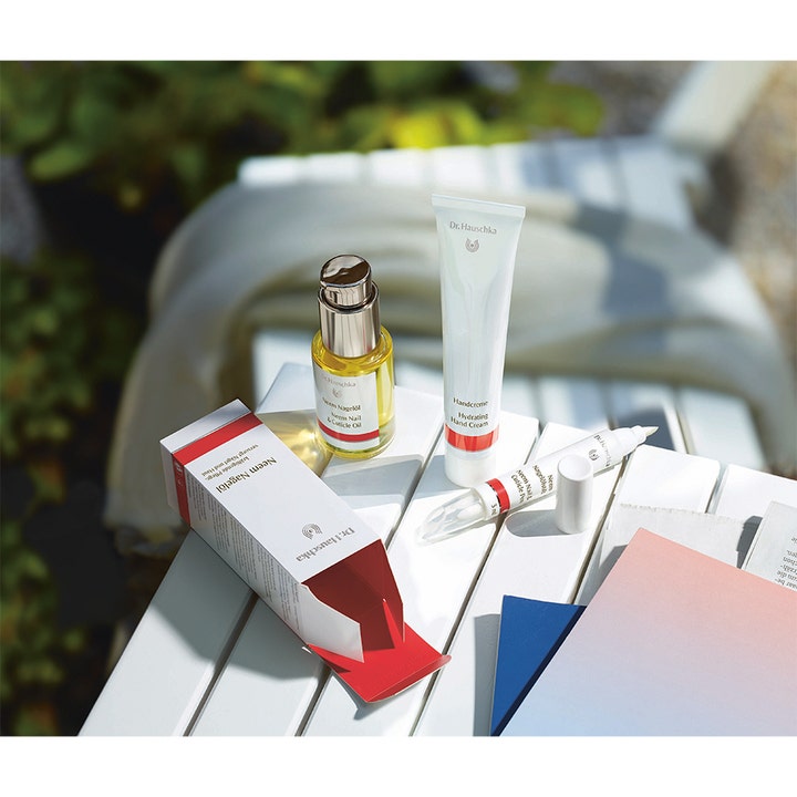 Dr. Hauschka Hand Cream 50 ml pleiende håndkrem i hvit tube i et utendørs miljø med andre negleprodukter